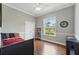 Cozy bedroom with a black bed frame, hardwood floors, a ceiling fan, and a window with a view of the front yard at 6132 Waterfield Way, St Cloud, FL 34771