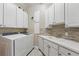 Functional laundry room with white cabinets, a sink with stone backsplash, and a washer and dryer set at 6132 Waterfield Way, St Cloud, FL 34771