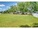 View of a home's backyard with a lush lawn and mature trees at 7316 Hunters Greene Cir, Lakeland, FL 33810