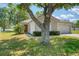 Front exterior view with a mature tree on a well-manicured lawn at 7316 Hunters Greene Cir, Lakeland, FL 33810