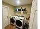 Spacious laundry room with washer, dryer, utility sink, and wire shelving at 74 N Oak Ave, Umatilla, FL 32784