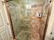 Walk-in shower featuring glass door, built-in shelves, and decorative tile surround at 74 N Oak Ave, Umatilla, FL 32784