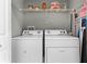 Bright laundry area equipped with a washer, dryer, and shelving for storage, offering practicality and organization at 7526 Pellham Way, Kissimmee, FL 34747