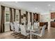 Bright dining room features a glass-top table, white chairs, and large windows with beautiful neutral-toned curtains at 7615 Brookhurst Ln, Kissimmee, FL 34747