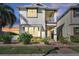 Charming two-story home featuring a small balcony, front garden with tropical plants, and brick-paved walkway at 8498 Powder Ridge Trl, Windermere, FL 34786