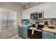Galley kitchen with white and blue cabinets, stainless steel appliances, and tiled backsplash at 8534 Crystal Cove Loop, Kissimmee, FL 34747