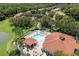 Aerial view of a community pool with a jacuzzi, chairs, and a restroom surrounded by trees and buildings at 8534 Crystal Cove Loop, Kissimmee, FL 34747