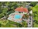 Aerial view of a community pool with a jacuzzi, chairs, and a restroom surrounded by trees and a parking lot at 8534 Crystal Cove Loop, Kissimmee, FL 34747