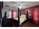 Comfortable bedroom with red accent wall, king-sized bed, dark wood furniture, and hardwood flooring at 8631 La Isla Dr, Kissimmee, FL 34747
