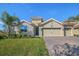 Beautiful single-story home featuring a stone facade, lush lawn, and a spacious two-car garage at 8999 Croquet Ct, Davenport, FL 33896