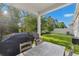 Covered outdoor patio with dining table, grill, and fenced in yard and mature trees at 1153 Augustus Dr, Davenport, FL 33896