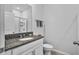 Bathroom featuring a granite countertop with a white cabinet, accompanied by a toilet and a framed mirror at 14419 Topaghan Way, Winter Garden, FL 34787