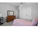 Cozy bedroom with soft pink bedding, featuring a classic dresser and a double door closet for ample storage at 14419 Topaghan Way, Winter Garden, FL 34787