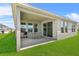 Covered patio with dining set and grill, seamlessly connected to the lush green backyard and exterior of the home at 14419 Topaghan Way, Winter Garden, FL 34787
