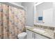 Well-lit bathroom features granite counters, white cabinetry, and coastal-themed shower curtain at 213 Strathmore Cir, Kissimmee, FL 34744