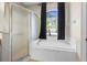 Bright bathroom featuring a garden tub, separate shower, and large window with black curtains at 213 Strathmore Cir, Kissimmee, FL 34744