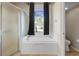 Bright bathroom featuring a garden tub, separate shower, and large window with black curtains at 213 Strathmore Cir, Kissimmee, FL 34744