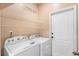 Bright laundry room with overhead shelving, modern machines, and a white door at 213 Strathmore Cir, Kissimmee, FL 34744