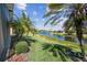 Scenic backyard view with a tranquil canal, lush green grass, and swaying palm trees at 238 Acadia Dr, Poinciana, FL 34759