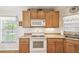 Bright kitchen with white appliances, wood cabinets, and window over the sink at 238 Acadia Dr, Poinciana, FL 34759