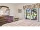 Peaceful main bedroom with lake views, with a dresser and mirror and chair situated near the window at 238 Acadia Dr, Poinciana, FL 34759