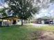 Spacious backyard featuring a large shade tree and a covered outdoor area at 2406 Thelma Ave, Haines City, FL 33844