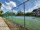 Outdoor tennis court with a high fence, trees and blue sky in the background at 2787 Oakwater Dr # 149, Kissimmee, FL 34747