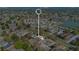 An aerial view displays community's residences, pond, mature trees, a common pool, parking areas, and its neighborhood at 31 Las Palmas Way, Kissimmee, FL 34743