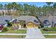 Aerial front view of a well-manicured home featuring a two-car garage, established landscaping, and mature trees at 310 N Hampton Dr, Davenport, FL 33897