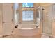 Bright bathroom features a tub beneath a window and a glass-enclosed shower at 310 N Hampton Dr, Davenport, FL 33897