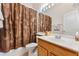 Bathroom with a shower and tub with a brown floral curtain, vanity, and mirror at 310 N Hampton Dr, Davenport, FL 33897
