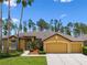 Charming mustard-colored single-Gathering home with a three-car garage and manicured lawn at 310 N Hampton Dr, Davenport, FL 33897