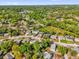 An aerial view of a suburban neighborhood featuring a mix of houses nestled among mature trees and a tranquil lake in the distance at 4410 Rossmore Dr, Orlando, FL 32810