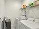 Efficient laundry room with a side-by-side washer and dryer, plus overhead shelving for added storage at 4623 Wandsworth Way, Davenport, FL 33837
