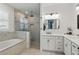 Modern bathroom features a soaking tub, glass-enclosed shower, and double vanity with neutral color palette at 4873 Old Oak Trl, St Cloud, FL 34771