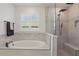 Relaxing bathroom showcasing a soaking tub, a window with shutter blinds, and a modern glass-enclosed shower at 4873 Old Oak Trl, St Cloud, FL 34771