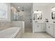 Bright bathroom featuring a soaking tub, glass-enclosed shower with dual shower heads, and double vanity with marble countertops at 4873 Old Oak Trl, St Cloud, FL 34771