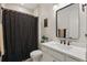 This bathroom features white cabinets, modern fixtures, and a shower/tub combination with a black shower curtain at 4873 Old Oak Trl, St Cloud, FL 34771