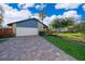 Charming home featuring a stone facade, blue accents, a paved driveway and well-maintained landscaping at 6051 Twin Lakes Dr, Oviedo, FL 32765