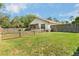Wide shot of the backyard showing the home with partial wooden fence and grassy space at 6495 Fall St, St Cloud, FL 34771