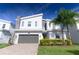 Modern two-story home with gray garage door, decorative stone accents, and well-manicured landscaping under blue skies at 8817 Cruden Bay Ct, Davenport, FL 33896
