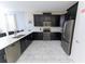 Modern kitchen with black cabinets, stainless steel appliances, and white marble-style floors and countertops at 8817 Cruden Bay Ct, Davenport, FL 33896