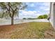 View of the spacious backyard with privacy fence, mature tree, and lush green grass at 105 Winchester Ln, Haines City, FL 33844