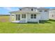 A view of the home's backyard, featuring a covered patio and AC unit at 1107 Olivine Ave, Dundee, FL 33838
