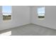 Neutral carpeted bedroom with white walls and two windows allowing natural light to enter at 1107 Olivine Ave, Dundee, FL 33838