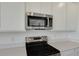 Close-up of stainless steel microwave and electric range cooktop, complemented by quartz countertops and white cabinets at 1107 Olivine Ave, Dundee, FL 33838