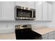 Close-up of the stainless steel microwave and oven with white quartz countertops and modern white cabinets at 1122 Olivine Ave, Dundee, FL 33838