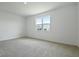 Bright, empty bedroom with neutral carpet, a large window, and white walls at 1134 Olivine Ave, Dundee, FL 33838