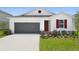 Front elevation featuring a white exterior, gray garage door, and fresh landscaping at 1134 Olivine Ave, Dundee, FL 33838
