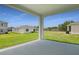 Covered patio with concrete flooring and white columns, overlooking the grassy lawn at 1134 Olivine Ave, Dundee, FL 33838